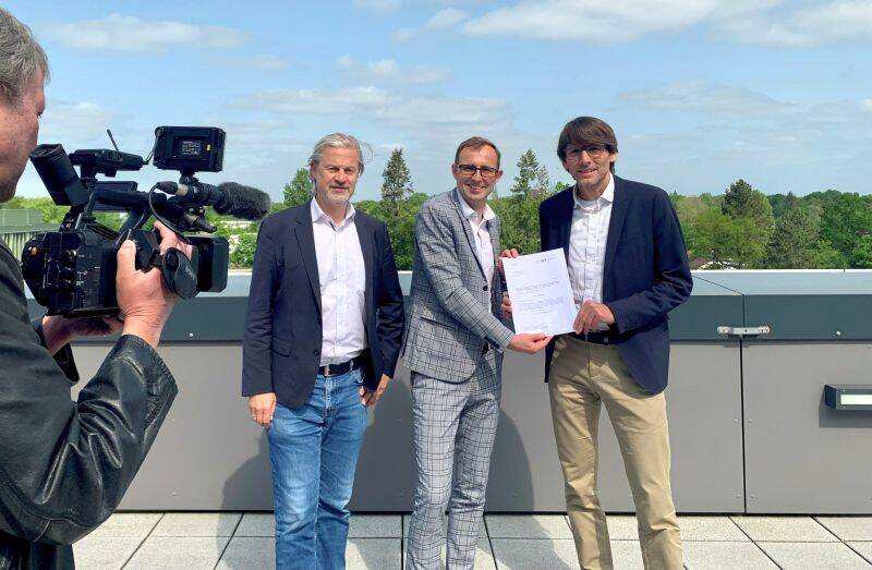 Digitalisierungsminister Dirk Schrödter (Mitte) übergibt an Prof. Jan Rupp (rechts) und Prof. Martin Leucker den Förderbescheid.