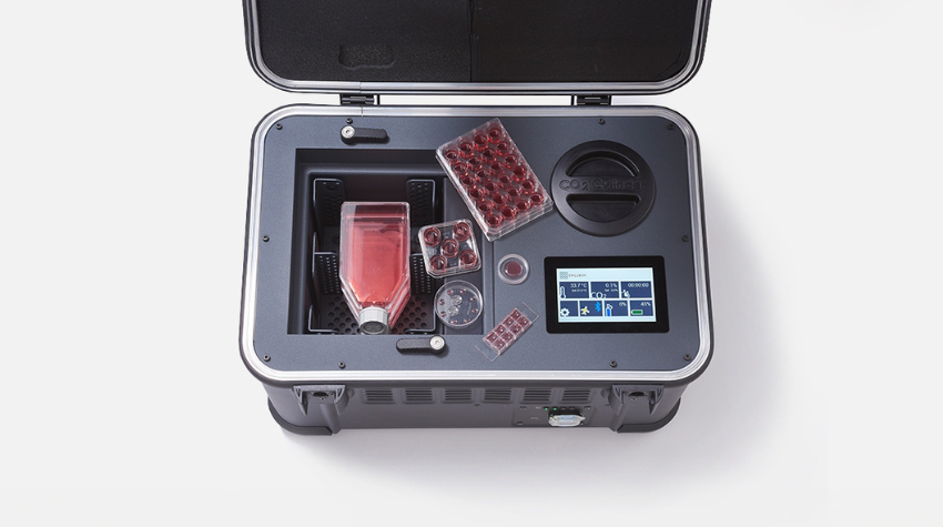 The lid of a black colored box is left open. Inside you can see flasks and well plates for stem cell culture with a red fluid in it. There is a small monitor embedded at the right side!